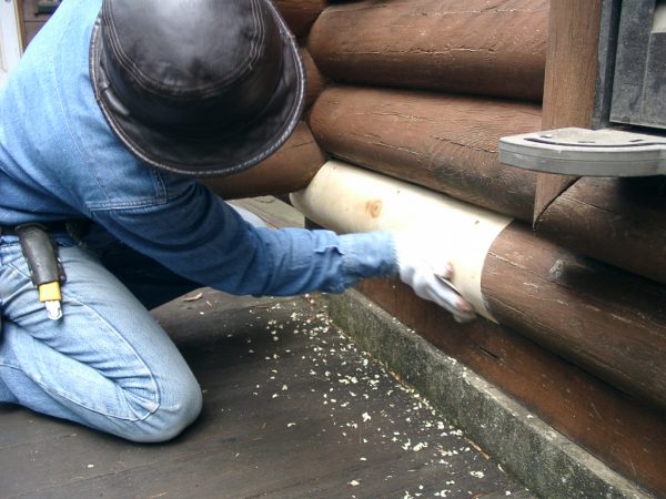 ログハウスをメンテナンス中の男